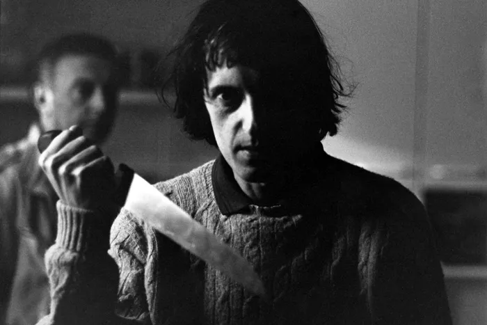 Black and white photo of Dario Argento holding a knife.